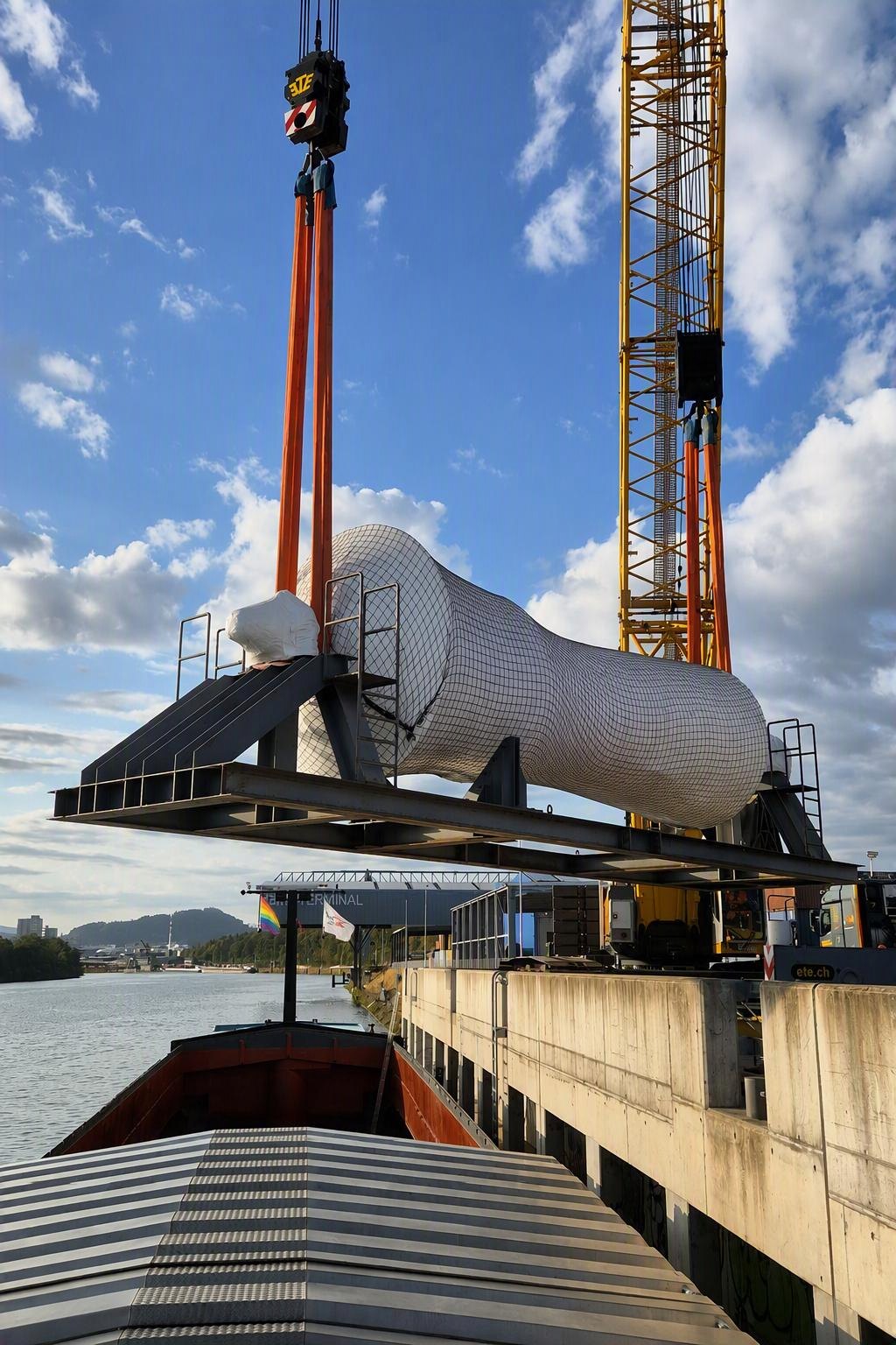 Schwere Projektladung wird am Birsterminal mit einem Kran in ein Binnenschiff verladen